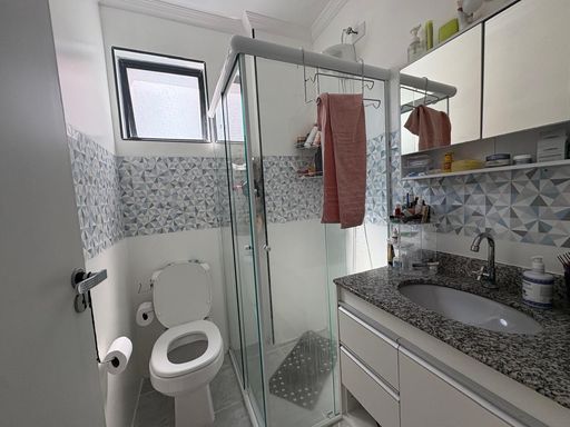 banheiro da suíte com armário planejado e box de vidro, bem arejado