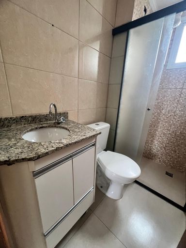 banheiro social com armário planejado e box de vidro, bem arejado