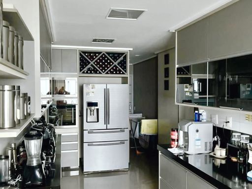 cozinha totalmente planejada e mobiliada com ampla pia em granito preta, semi integrada a área de serviço