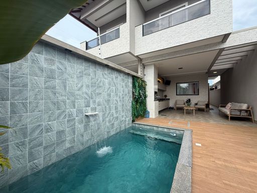 área gourmet com piscina, cascata, iluminação noturna e churrasqueira a carvão