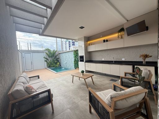 área gourmet com piscina, cascata, iluminação noturna e churrasqueira a carvão