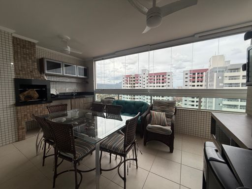 ampla varanda gourmet envidraçada com cortina blackout, armários planejados e churrasqueira a carvão