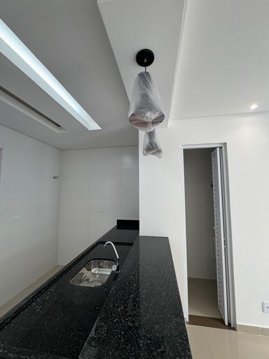 cozinha com ampla pia em granito preta semi integrada a sala 2 ambientes e ao lavabo