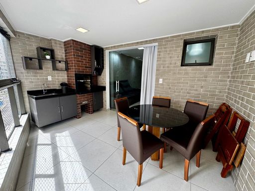 ampla varanda gourmet envidraçada com tela de proteção, churrasqueira a carvão, armário planejado e pia em granito preta