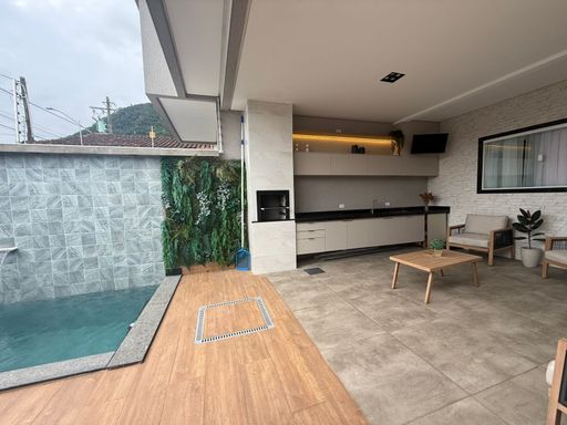 área gourmet com piscina, cascata, iluminação noturna e churrasqueira a carvão