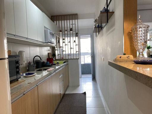 cozinha com armários planejados semi integrada a área de serviço, com acesso a varanda