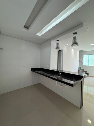 cozinha com ampla pia em granito preta semi integrada a sala 2 ambientes e ao lavabo, com sistema de iluminação diferenciada e teto rebaixado