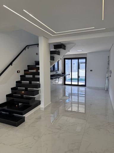 sala 2 ambientes integrada a cozinha e acesso a piscina e as escadas em granito preto para o piso superior