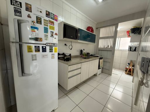 ampla cozinha com armários planejados, acesso a área de serviço bem arejada com porta de correr