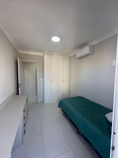 Dormitório com armário planejado, ar condicionado e acesso a varanda envidraçada
