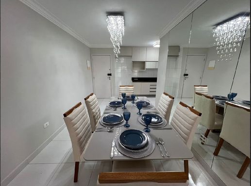 Sala de jantar com parede espelhada, acesso a entrada principal, semi integrada a cozinha.
