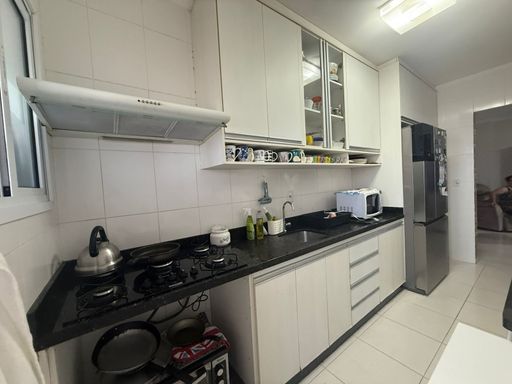 cozinha com armários planejados, ampla pia em granito preta e acesso a área de serviço arejada e bem iluminada