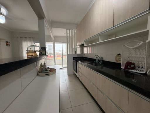 cozinha padrão americana com planejados, ampla pia em granito preta, semi integrada a área de serviço com acesso a varanda gourmet