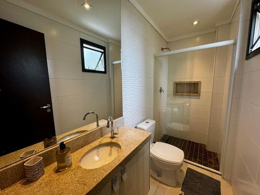 banheiro social com ampla pia em granito e armário planejado, nicho e box de vidro