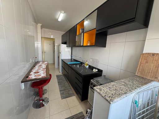 cozinha com armários planejados semi integrada a área de serviço e acesso a entrada principal