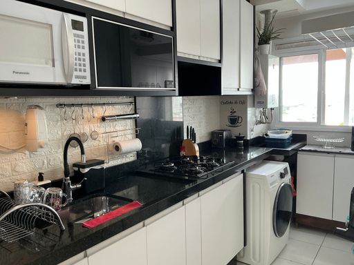 cozinha com móveis planejados com ampla pia em granito preto, semi integrada a área de serviço