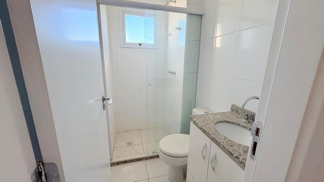 banheiro da suíte arejado com box de vidro e armário embutido