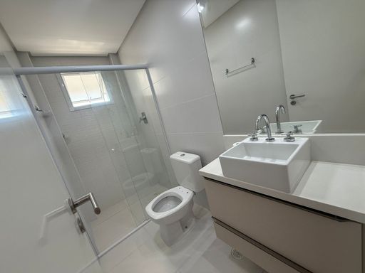 banheiro da suíte bem arejado, com box de vidro e armário planejado