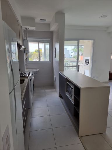 Cozinha com móveis planejados semi integrada a área de serviço e a sala 2 ambientes com acesso a varanda gourmet