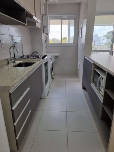 Cozinha com móveis planejados semi integrada a área de serviço bem arejada