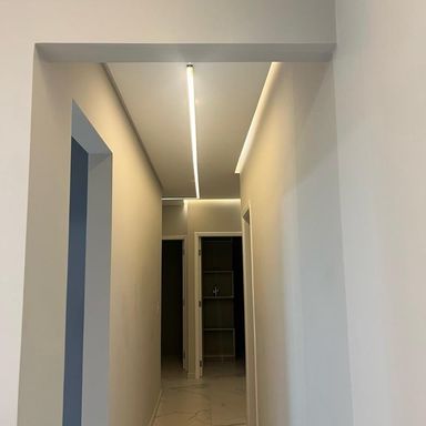 corredor com sistema de iluminação em LED e teto rebaixado, com acesso aos dormitórios