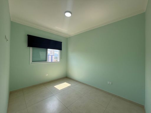 amplo dormitório com iluminação natural e persiana de rolo