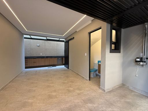 área gourmet externa retrátil com pia ampla e bancada em granito preta, com armários planejados e acesso a garagem com lavabo
