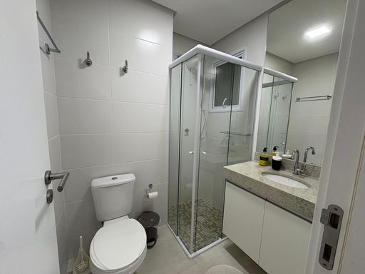 Banheiro social bem arejado com armário planejado e box de vidro