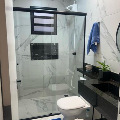 banheiro da suíte bem arejado, com box blindex, nicho e ampla pia em granito preta