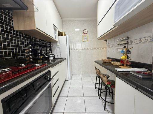 cozinha com armários planejados, ampla pia e balcão em granito preto