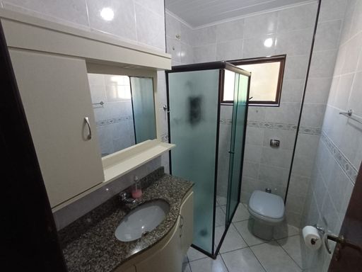 banheiro social bem arejado com armário planejado e box de vidro