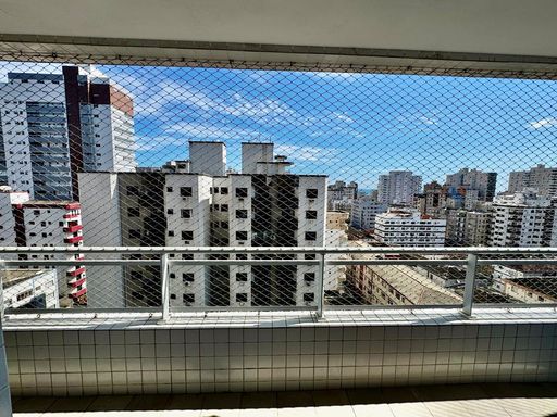 ampla varanda gourmet com pequena vista mar, com tela de proteção e acesso as suítes