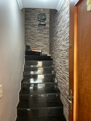 Entrada principal com escada em granito preta e acesso ao piso superior