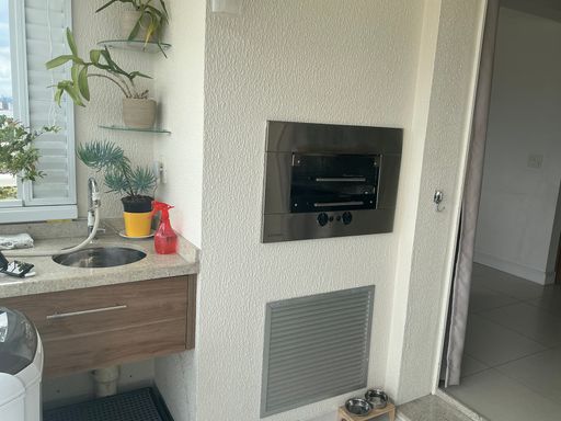 ampla varanda gourmet envidraçada com móveis planejados e churrasqueira