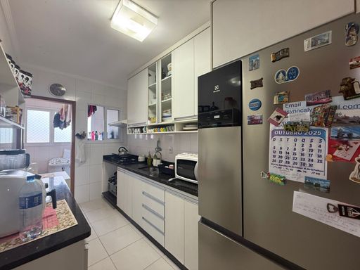 cozinha com armários planejados, ampla pia em granito preta e acesso a área de serviço arejada e bem iluminada