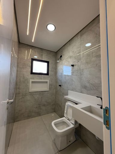 banheiro da suíte bem arejado com nicho e sistema de iluminação em LED com teto rebaixado