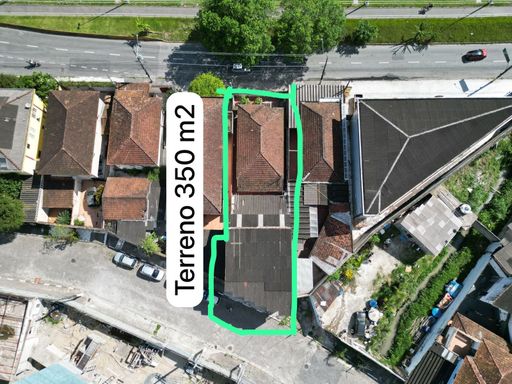 terreno completo para venda com a casa sobreposta alta e garagens em um dos lados, do outro lado fica uma casa usada atualmente como pousada