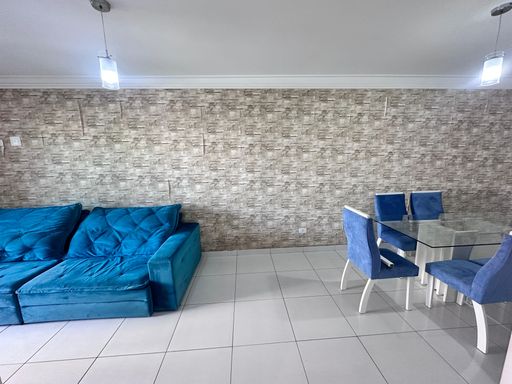 Sala com dois ambientes, equipada com sofá, painel de TV, mesa de jantar para seis pessoas e espelho de parede.
