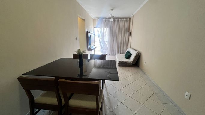 Sala de 2 ambientes com sofá, painel de TV e mesa de jantar.