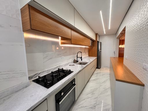 Cozinha americana iluminada, com armários planejados e iluminação em LED.