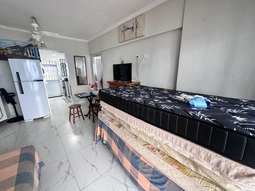 Sala ampla com ventilador de teto e sacada com vista para o mar.