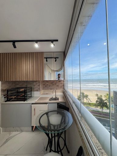 Sacada gourmet envidraçada com vista para o mar.