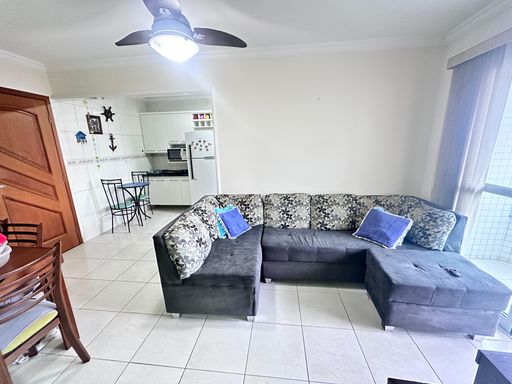 Sala bem iluminado com um sofá, ventilador de teto e uma sacada.