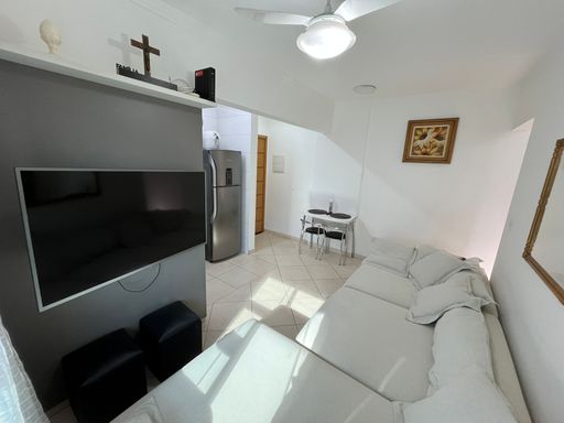 Sala com um sofá cinza, ventilador de teto e sacada.