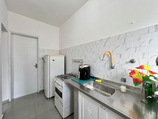 Cozinha com uma pia e gabinete embutido, fogão e geladeira.