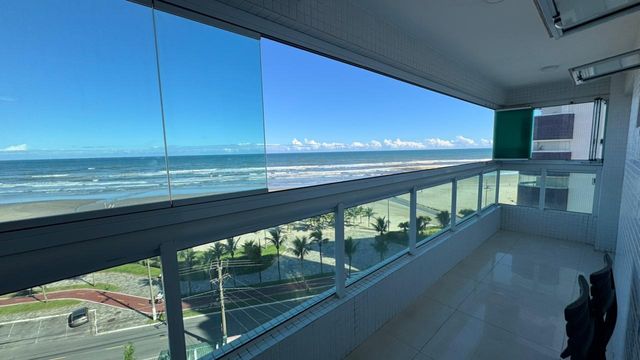 Sacada gourmet envidraçada com vista para o mar.