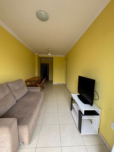 Sala de 2 ambientes com paredes amarelas, mesa, sofa e ventilador de teto.