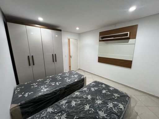 Dormitório com 2 camas de solteiro, armário planejado e painel de TV.