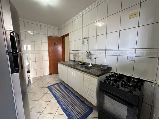 Cozinha com armários brancos, pia, gabinete,  geladeira e fogão.