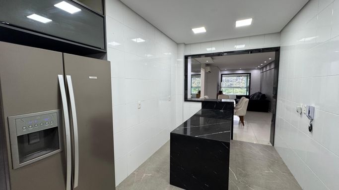 Cozinha americana totalmente planejada com geladeira de duas portas.